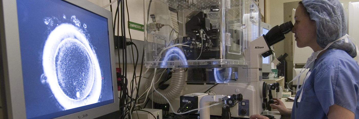 Woman in lab looking through a microscope