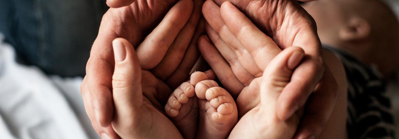 Two adult hands cradling babies feet